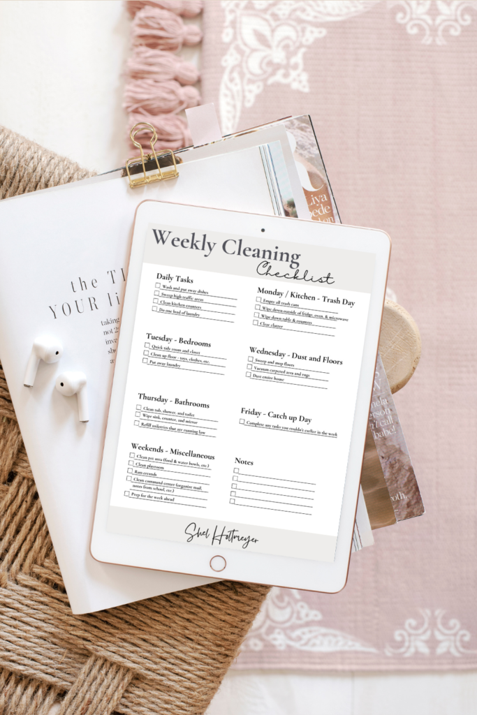pages held together with a paper clip,  with airpods on top, under an ipad that shows the weekly cleaning list freebie included in the post. 
