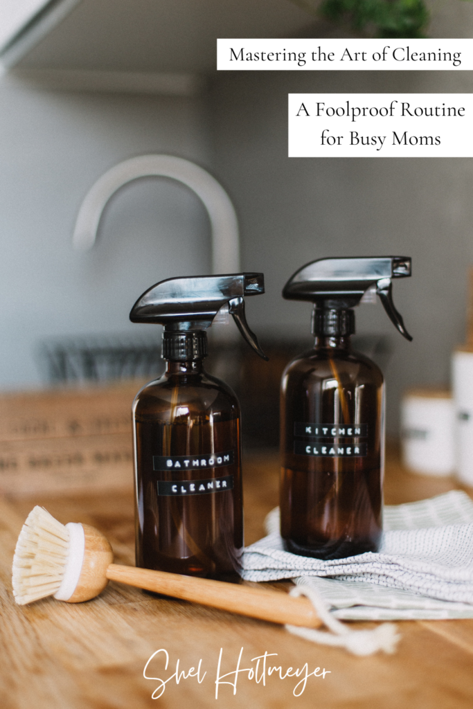 Mastering the Art of Cleaning: A foolproof routine for busy moms featured image, showing two spray bottles with bathroom cleaner and kitchen cleaner labels, next to hand towels and a brush on a kitchen counter.